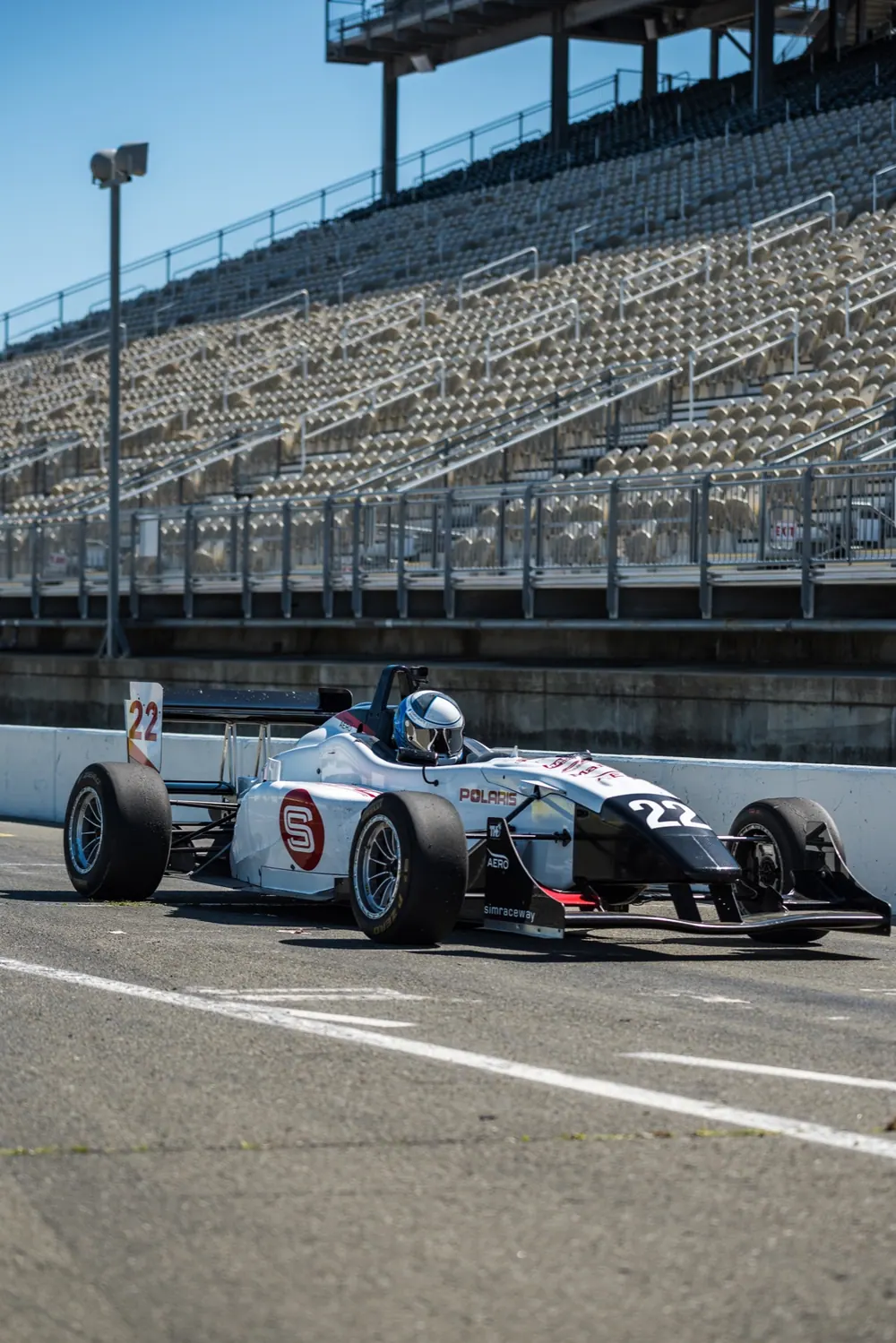 Jeff Kirk seated in Formula 3 car number 22 beside the grandstand